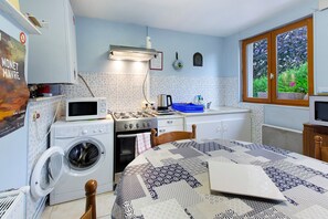 A compact kitchen with a washing machine, a stove, and a sink.