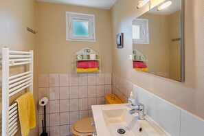 Une salle de bain équipée de toilettes, d’un lavabo, d’un porte-serviettes et d’un miroir.