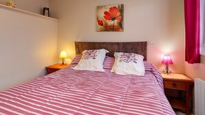 A neatly made bed with striped bedding, a headboard, two bedside lamps, and a wall-mounted painting of red flowers. - Guest Room 'Chambre Lecarpentier - Coquelicot' with Shared Terrace, Shared Garden, Wi-Fi (Fontenay)