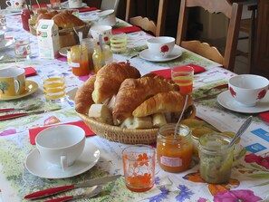 Een ontbijtsetting met croissantjes, koffiekopjes en een rieten mand.