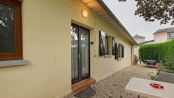A building with a beige exterior, a door with a glass panel, and a small outdoor seating area with a table and chairs.