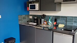 Une cuisine moderne avec un mur d’accent bleu, un four à micro-ondes, une machine à café et un lave-vaisselle.