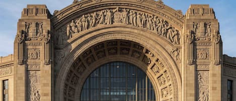 A grand building with a large arched entrance, detailed stone carvings, and a green awning.