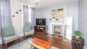 A living room with a fireplace, a television, and two sofas. - Queen City Suites 2 For 4 (Cincinnati)
