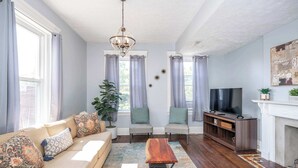 A living room with a sofa, chairs, a coffee table, a TV, and a fireplace. - Queen City Suites 2 For 4 (Cincinnati)