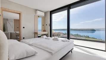Un dormitorio moderno con una cama grande, un escritorio y vistas a un lago.