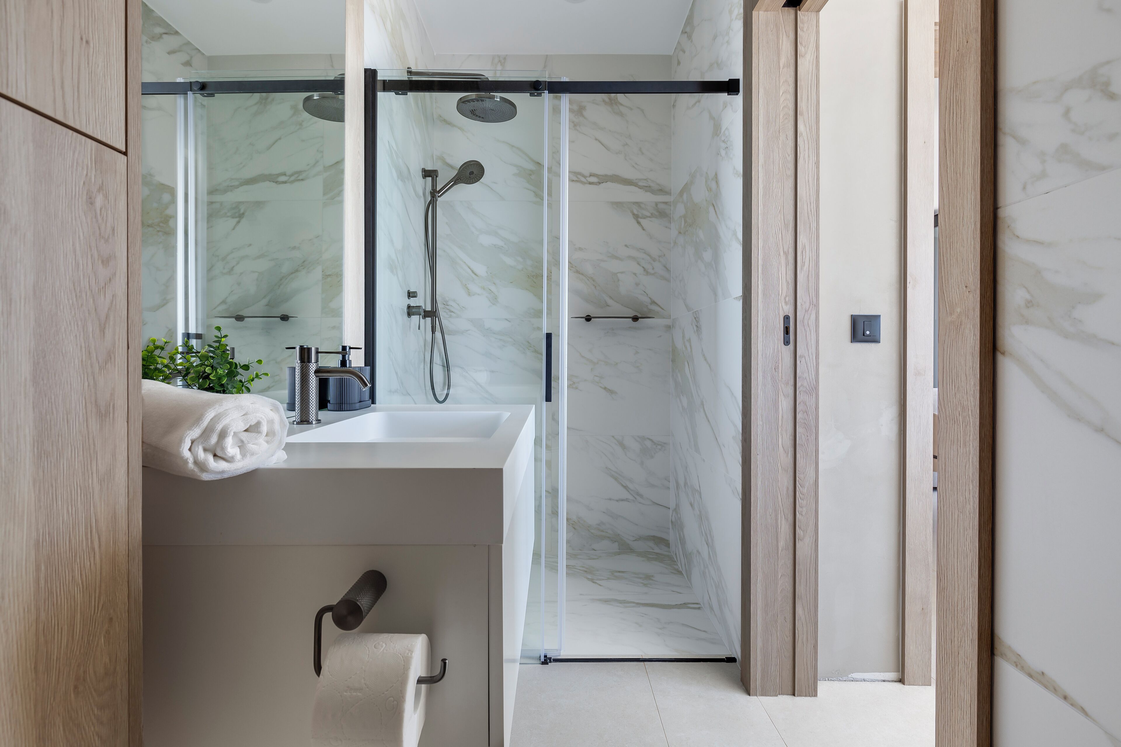 Une salle de bain moderne avec une douche à parois de verre, un lavabo blanc et un porte-serviettes.