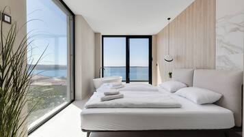 Ein modernes Schlafzimmer mit einem großen Bett, Meerblick und minimalistischem Design.