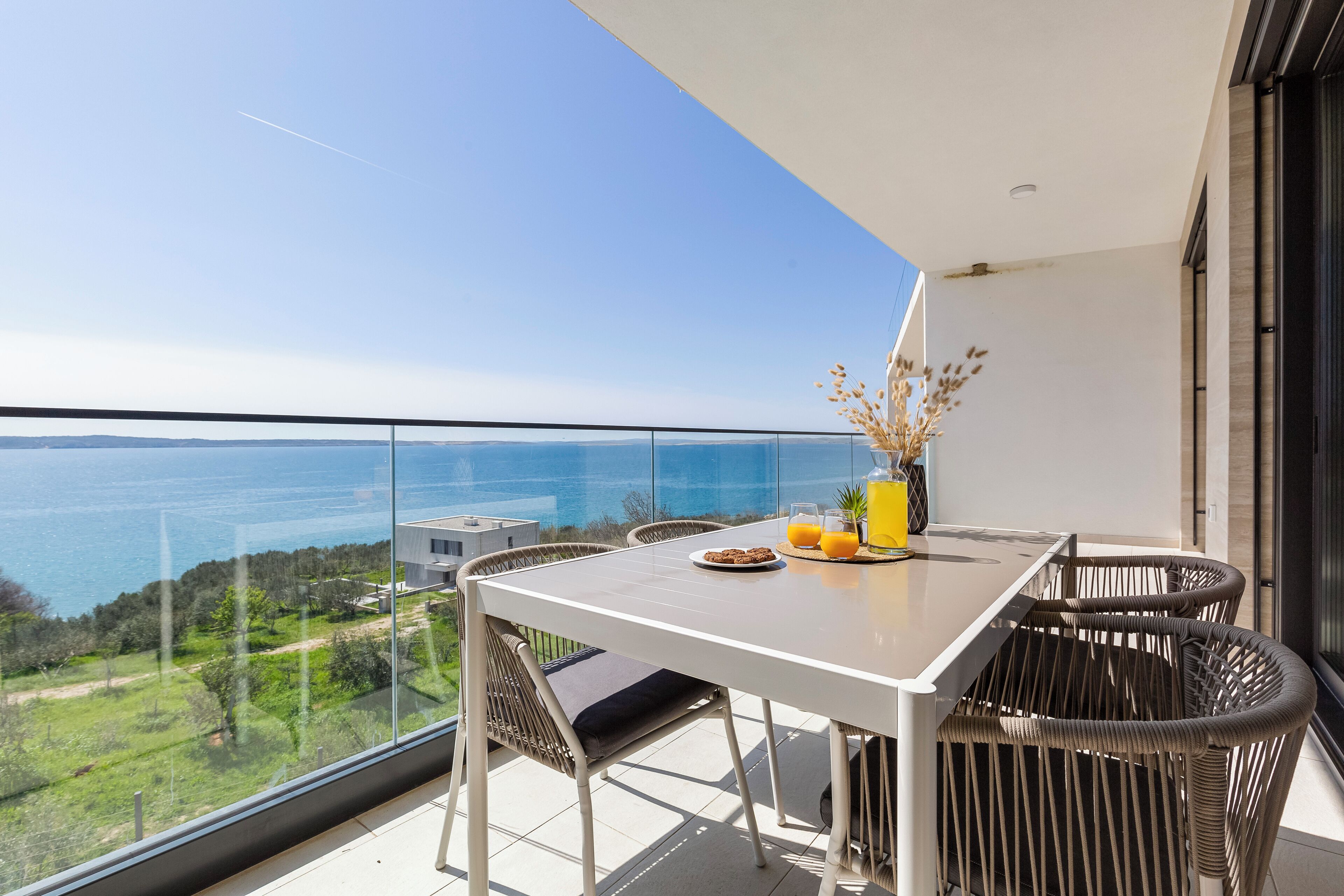 Un balcón con mesa, sillas y vista al mar.