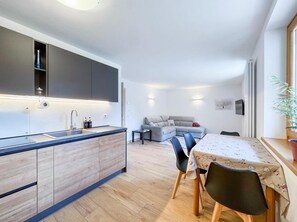 A modern kitchen with a built-in island, a dining area with a table and chairs, and a living room with a sofa.