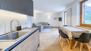 Una cucina moderna con lavello integrato e un'area pranzo con tavolo e sedie.