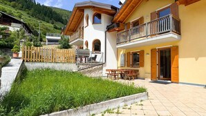 Un edificio a due piani con un balcone, un vialetto in pietra e una zona verde.