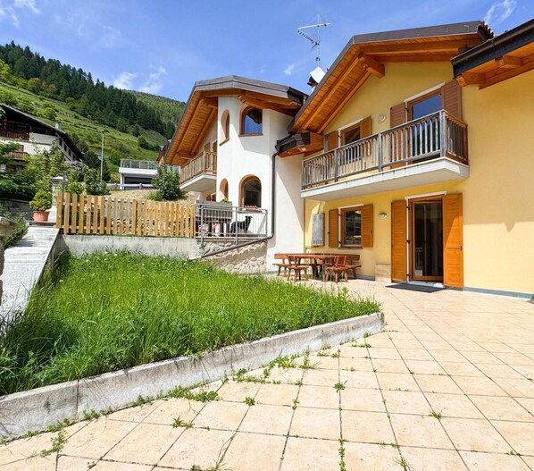 A two-story building with a balcony, a stone pathway, and a grassy area.