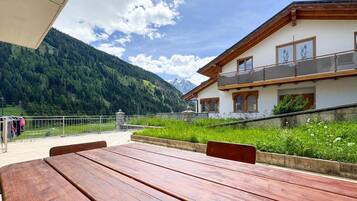 Un pontile in legno con vista su una montagna e un edificio con balconi.