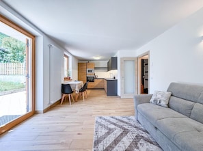 A modern apartment with a dining area, kitchenette, and a grey sofa.
