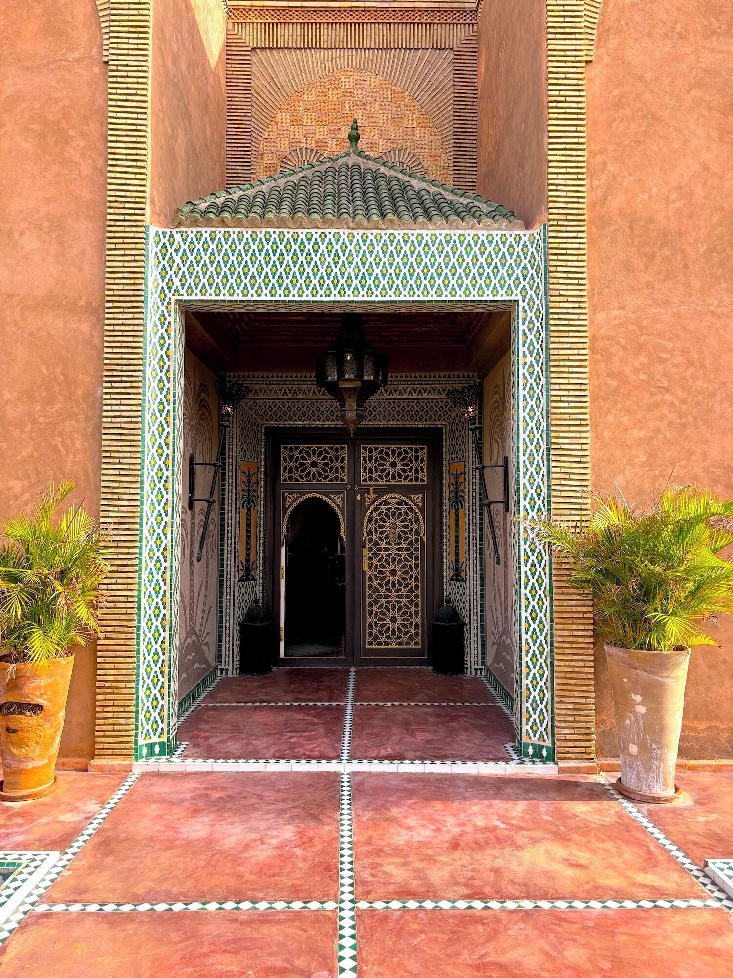 A traditional entrance with intricate tile work and a tiled floor leading to a dark doorway.