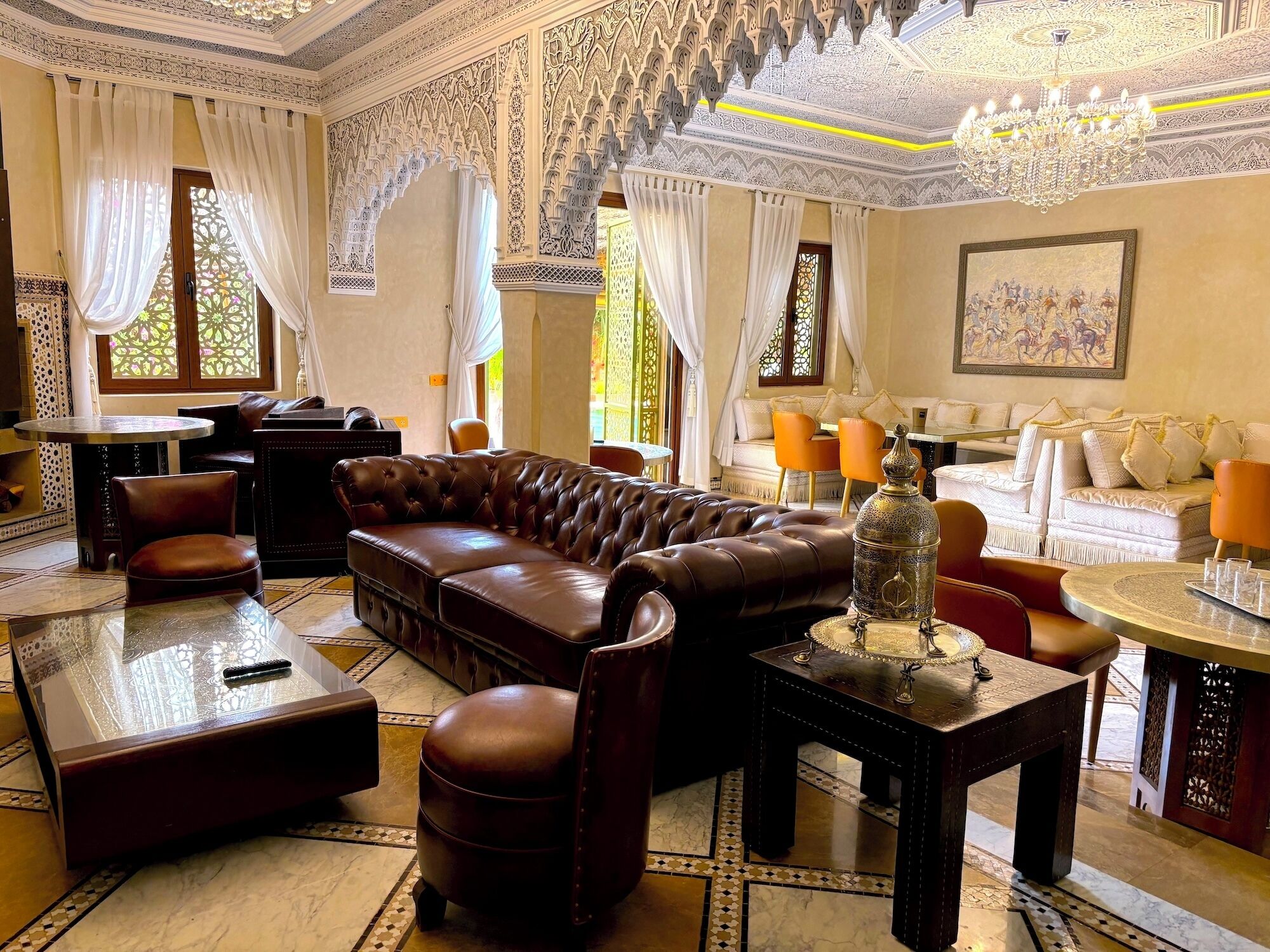 A luxurious living room with a brown leather sofa, a coffee table, and a patterned floor.