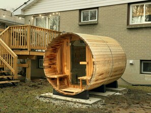 A cylindrical wooden structure with seating inside, positioned on a concrete base outdoors.