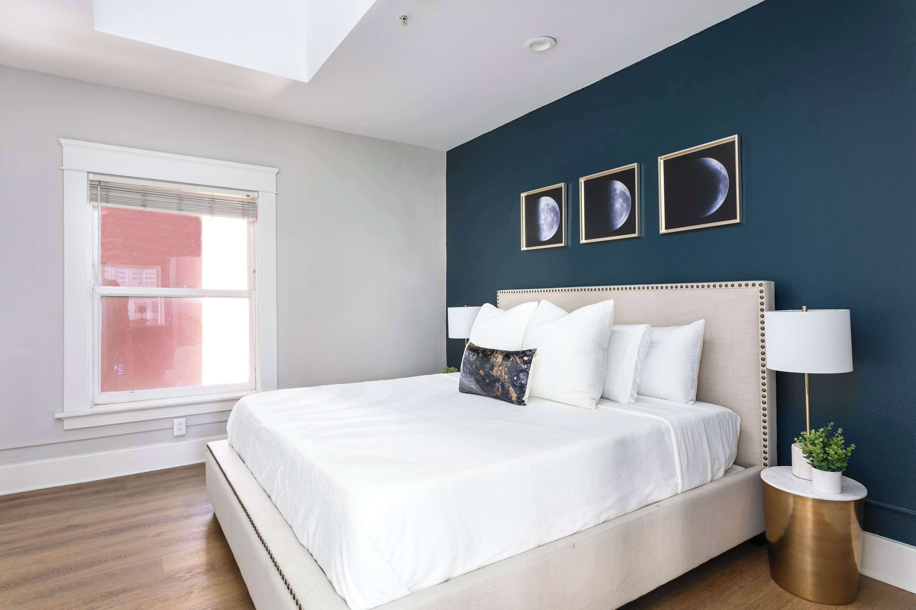 A bedroom with a large bed, a bedside lamp, and a window with blinds.