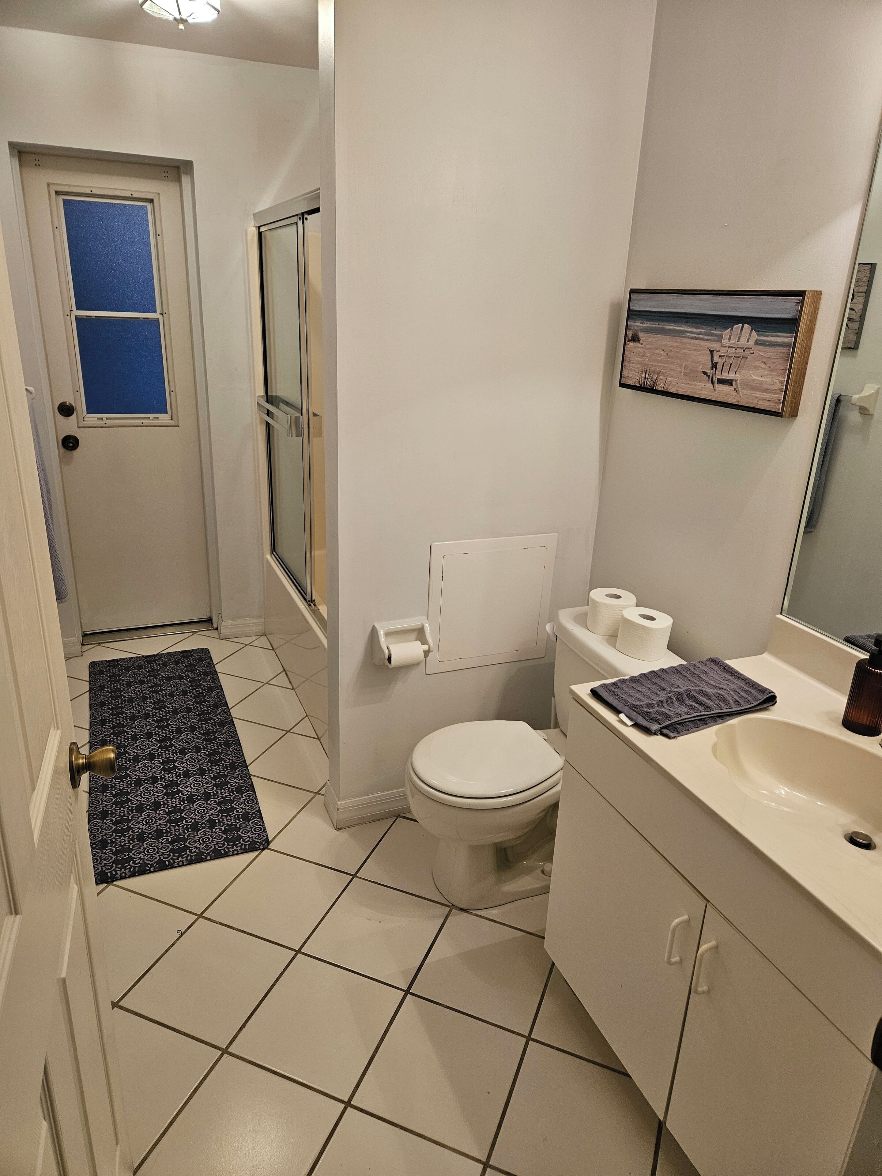 A bathroom with a toilet, sink, and a blue mat.