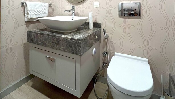 Un baño con lavamanos, tocador, espejo y retrete.