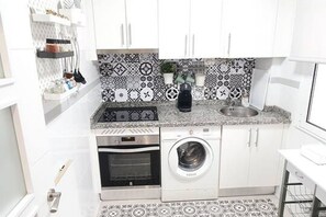 Une cuisine compacte équipée d’un lave-linge, d’un four et d’un crédence décorée.