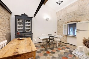 Una habitación con una mesa de madera, sillas, un aparador con puertas de vidrio, una ventana y un piso estampado.