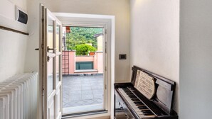 A piano in a room with a door leading to an outdoor area. - Room 'Stanza Della Musica' with Sea View, Shared Terrace and Wi-Fi (CERIALE)