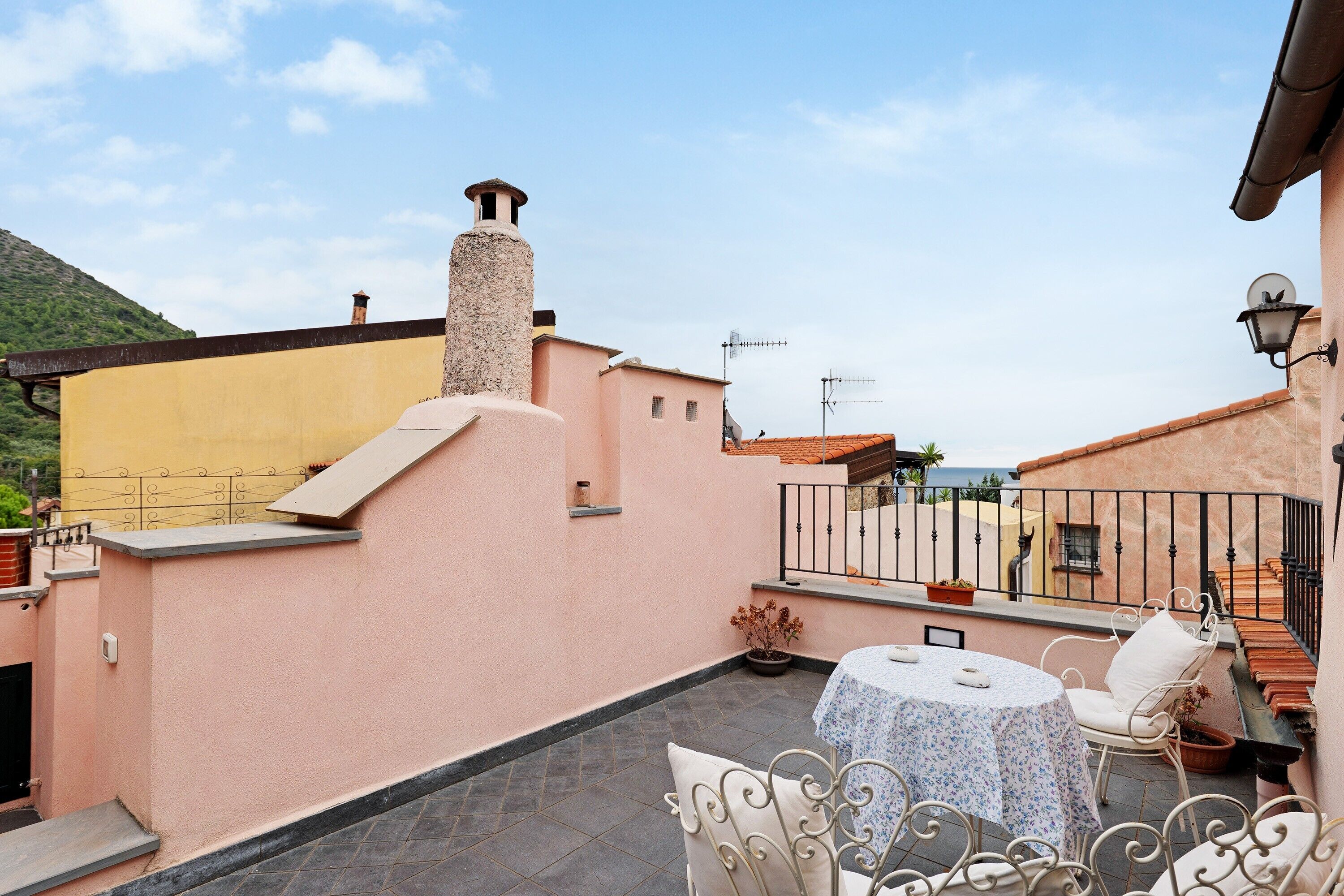 Una terrazza sul tetto con tavolo e sedie, un camino e vista sugli edifici circostanti.