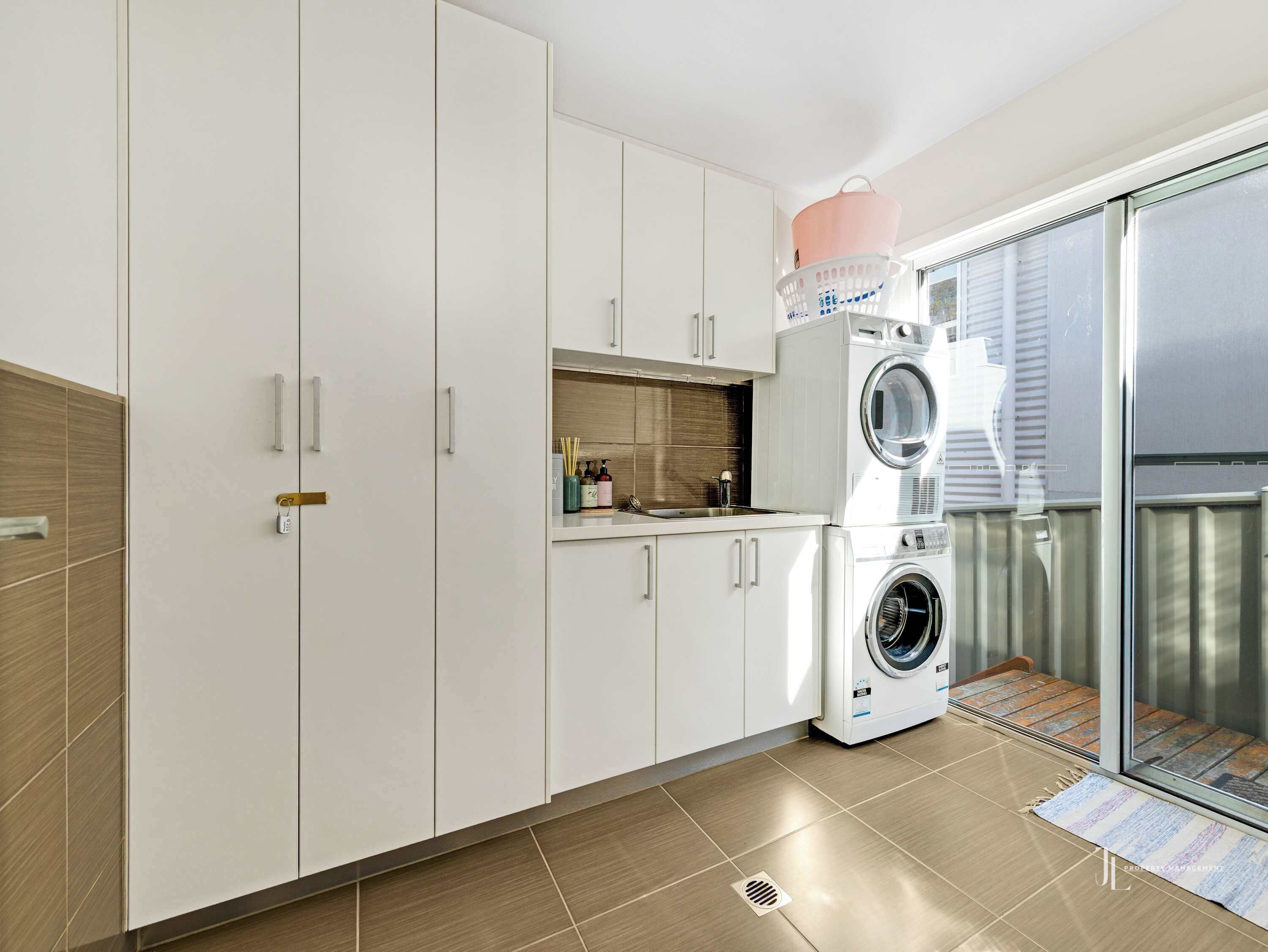 Une cuisine moderne avec des meubles blancs, un lave-linge encastré et une petite fenêtre.