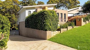 A modern two-story house with a driveway leading to a gated entrance.