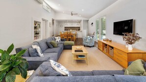 A modern living room with a grey sofa, a wooden coffee table, and a TV on the wall.