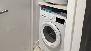 Ein kleiner Waschraum mit einer Waschmaschine mit Frontlader und einem darüber angebrachten Trockner.