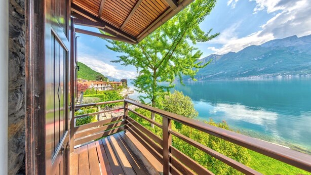 A wooden deck with a railing overlooking a lake and mountains.