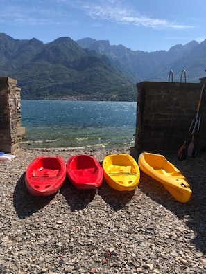 Une côte rocheuse avec quatre kayaks, un mur de pierres et une chaîne de montagnes en arrière-plan.