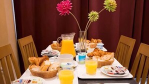 A breakfast table with croissants, juice, and pastries. - Hotel Audran (Paris)
