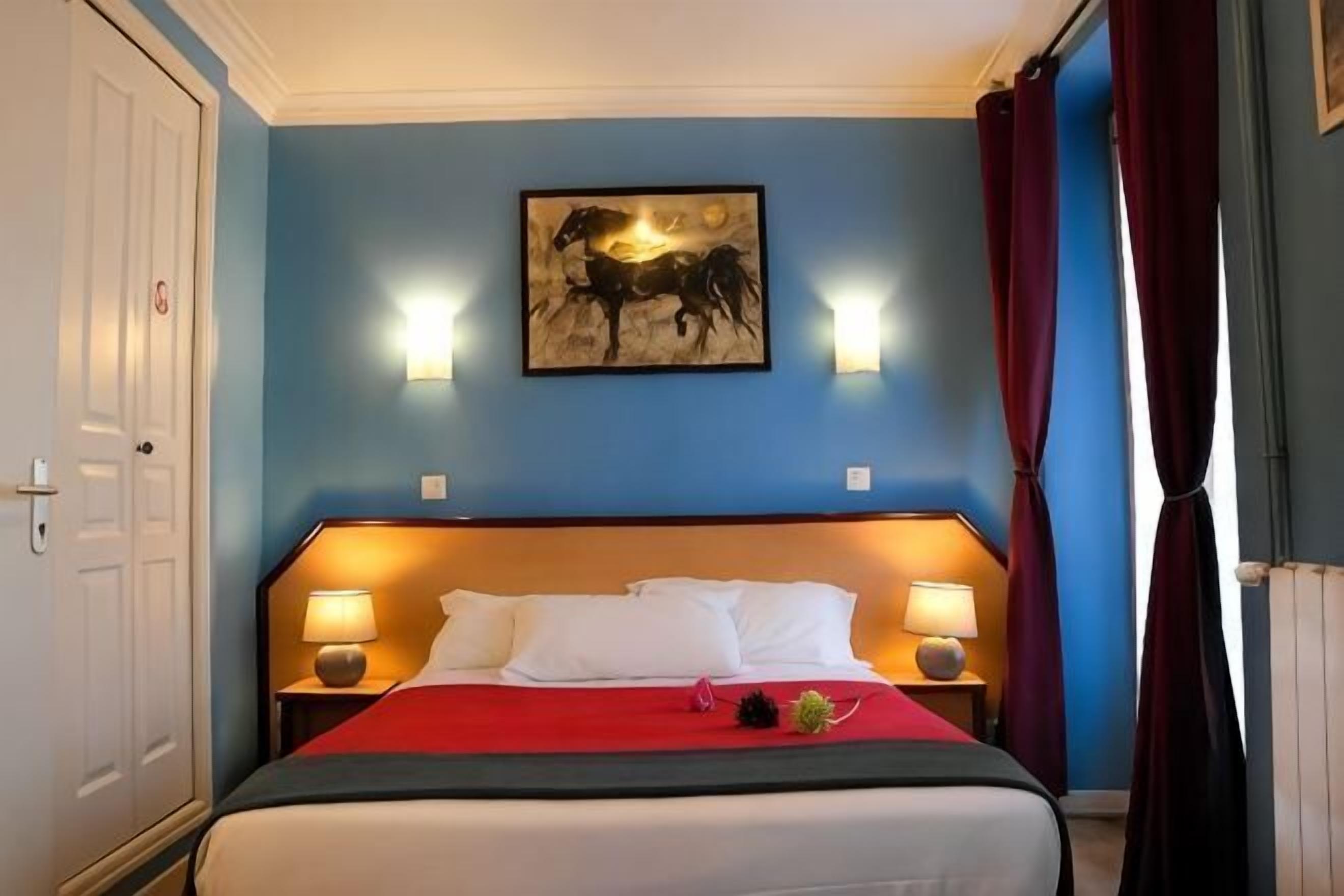 Hotelkamer met een bed, twee bedlampen, een kunstwerk aan de muur en een deur.
