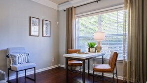 Un coin repas comprenant une table, des chaises et une fenêtre avec des stores.