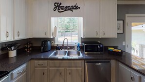 Una cocina con armarios blancos, una cafetera, un microondas y un lavavajillas.