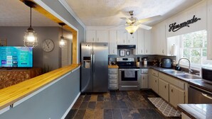 Una cocina moderna con armarios blancos, electrodomésticos de acero inoxidable y encimera de madera.