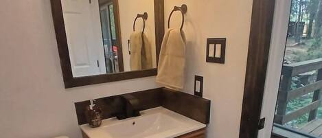 Een badkamer met een wit toilet, een houten wastafelmeubel en een spiegel met verlichting.