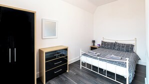 Un dormitorio con cama, armario, mesita de noche y tocador.
