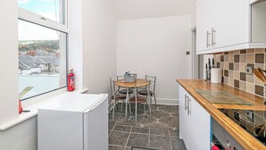 Una cocina compacta con ventana, una pequeña mesa con sillas y salpicadero de azulejos.
