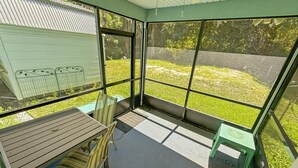 Une pièce lumineuse, avec une table et des chaises, de grandes fenêtres et une vue sur une cour verdoyante.
