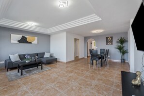 A modern living room with a sofa, coffee table, and dining area.