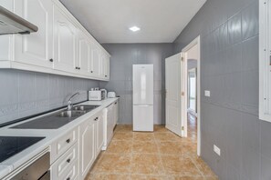 A kitchen with white cabinets, a sink, a stove, and a refrigerator.