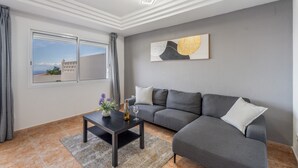 A modern living room with a grey sofa, a coffee table, and a painting on the wall. - Vacation Apartment 'Ocean View Costa Adeje' with Sea View, Private Terrace and Wi-Fi (Costa Adeje)