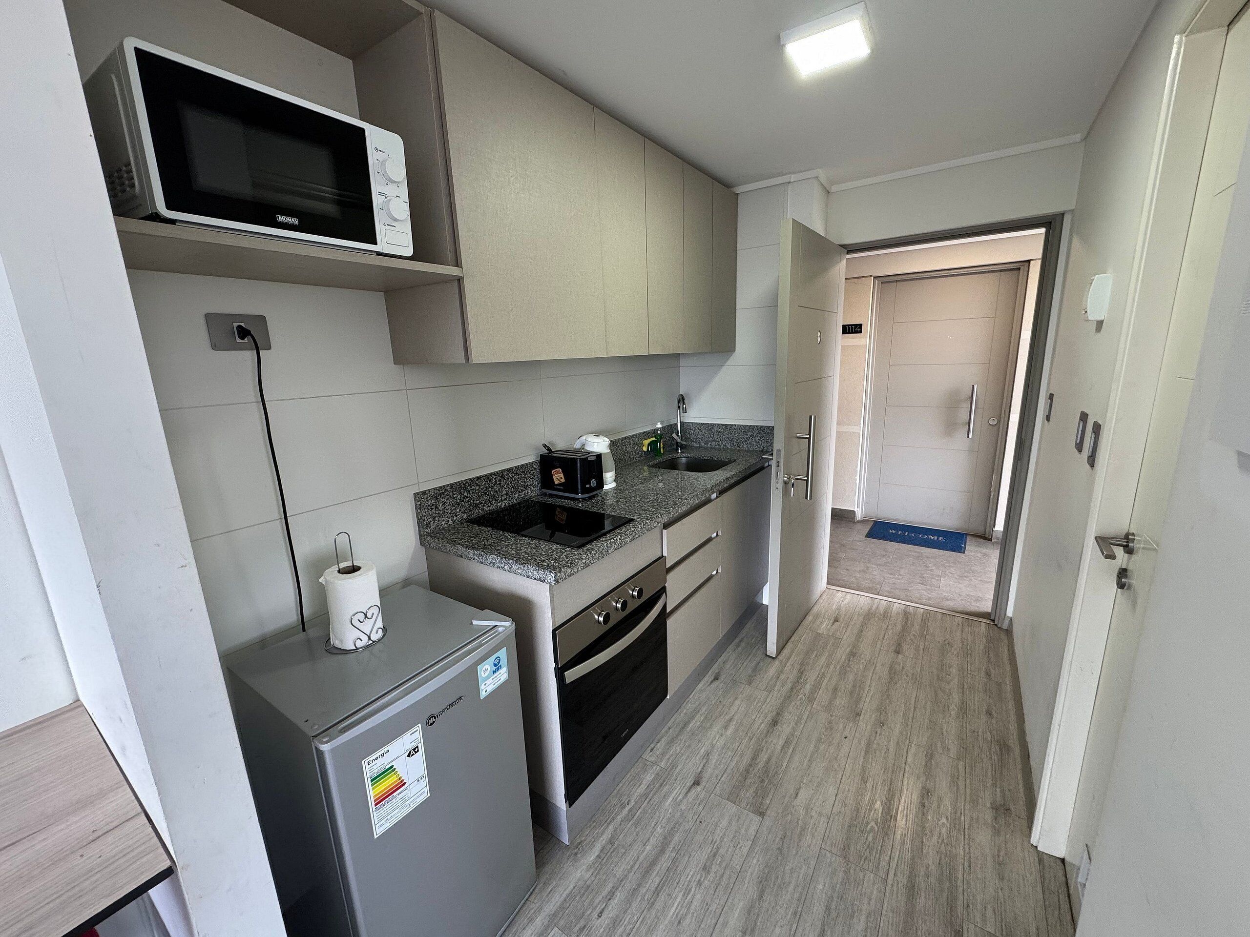 Cocina compacta con microondas, tostadora, fregadero y refrigerador.