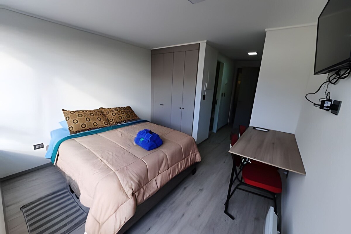 A bedroom with a bed, a desk, and a wardrobe.