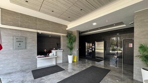 Ein moderner Empfangsbereich mit einer Rezeption, einer großen Pflanzung und einem Glaselevator.